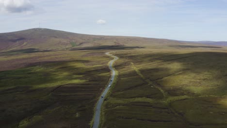 Luftaufnahme-Von-Autos,-Die-An-Einem-Sonnigen-Tag-Auf-Einer-Langen,-Kurvenreichen-Bergstraße-In-Den-Wicklow-Mountains-Fahren-3