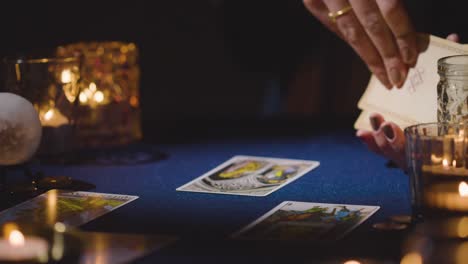 close up of woman giving tarot card reading on candlelit table holding the tower card 4