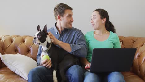a young caucasian couple talking and paying their bills using a laptop