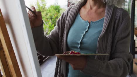 mujer de raza mixta de alto nivel pintando en el balcón