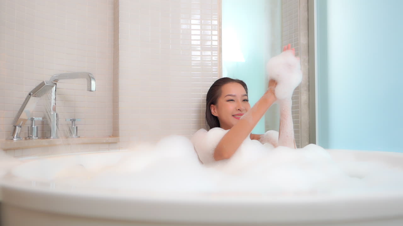 호텔 방 안에 거품이 가득한 욕조에서 휴식을 취하는 뜨거운 목욕을 하는 여자