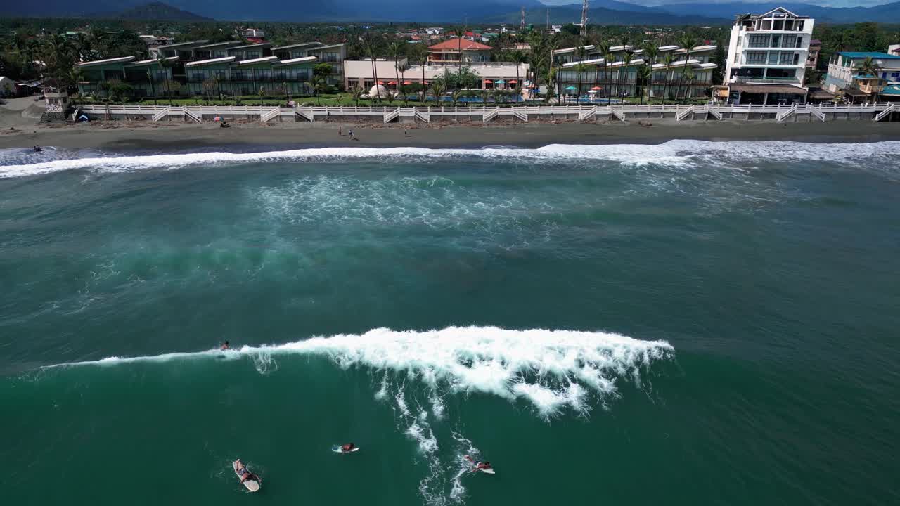 A wide drone shot captures the vast ocean, with waves rolling gently toward the shore, creating a rhythmic and peaceful scene.
