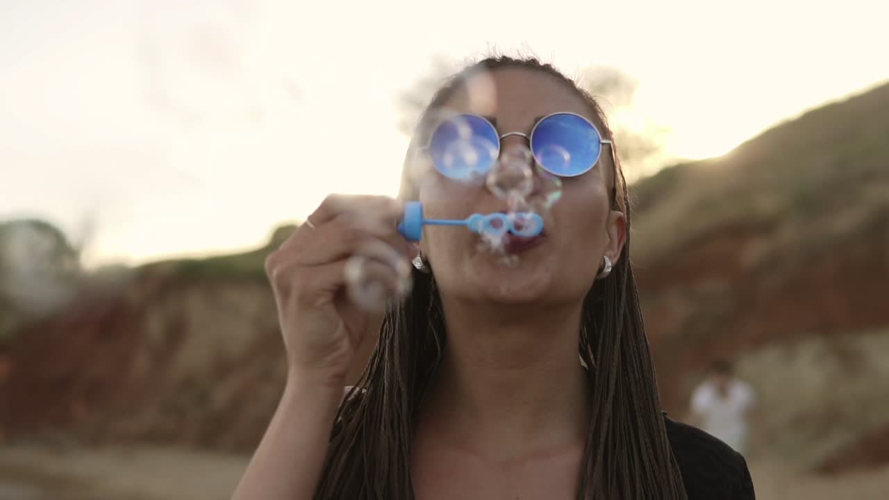 una joven hipster con pañales haciendo burbujas de jabón en la playa por la noche. disparo en cámara lenta