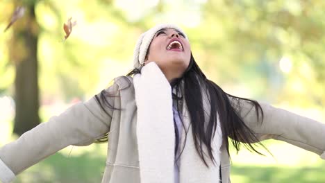 attractive girl tossing colorful autumn leaves up in air in park