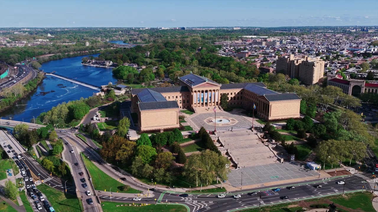 Luftfoto med drone av Philadelphia Museum of Art på toppen av Fairmount-åsen, med Schuylkill River, omkringliggende parkveier og et vidstrakt bybilde, alt synlig