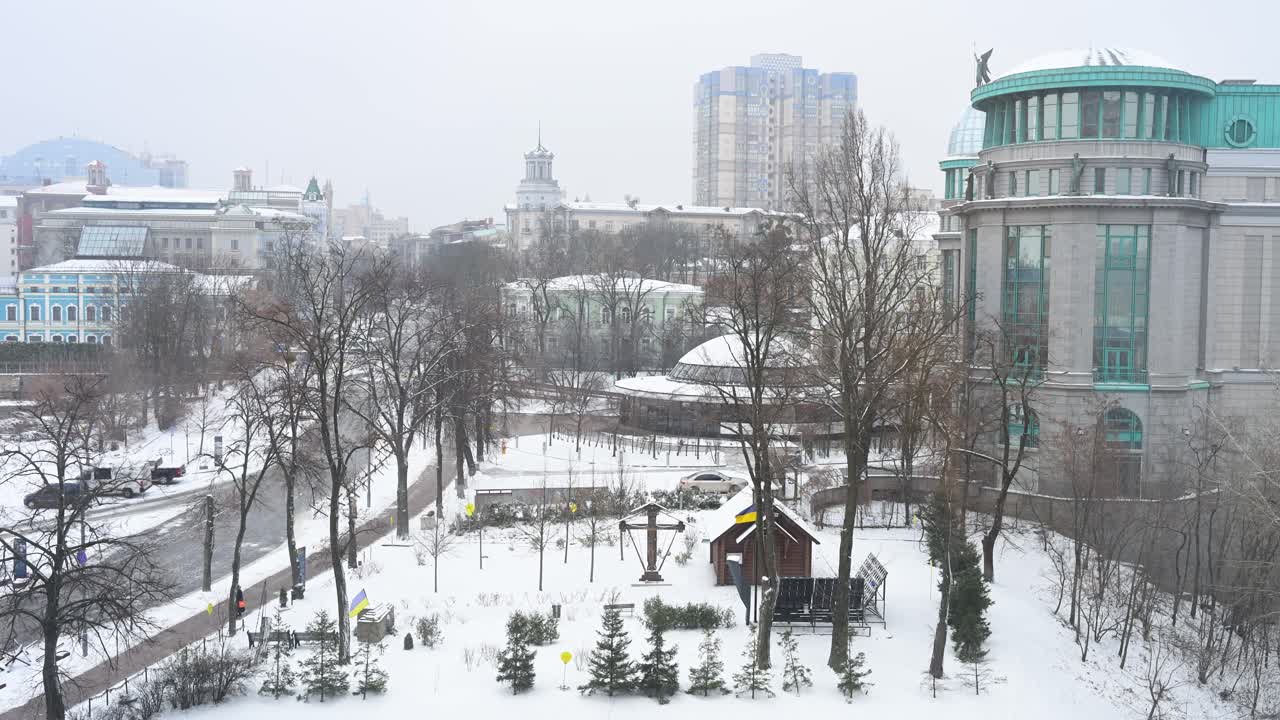 Winter transforms the urban landscape into a serene, snow-covered panorama in Kyiv, Ukraine. Bare trees and city architecture stand against cold skies, capturing the capital's stark beauty.