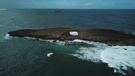 waves crashing against natural sea arch at laie point, o'ahu hawaii, aerial view