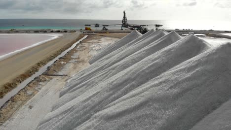 volando sobre las pilas de sal blanca en bonaire en contraste con los coloridos estanques de sal rosa y el océano turquesa