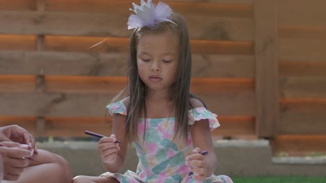 a mother and her young daughter sit on a blanket in the backyard, engaging in a drawing activity together. the outdoor scene captures a peaceful family moment, fostering creativity and bonding.