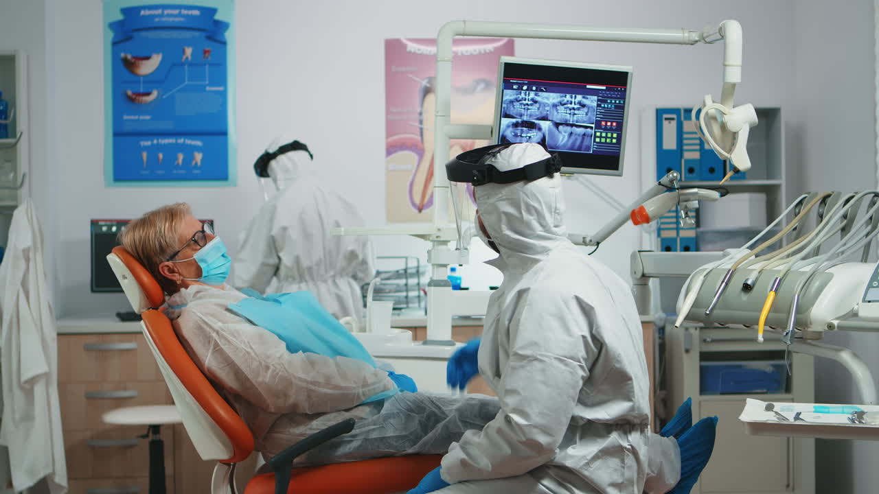 paciente hablando con un médico vestido con un traje de protección