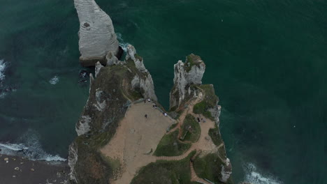 Tourists-on-viewing-platform-above-Etretat-Cliffs,-Aerial-tilt-down-view