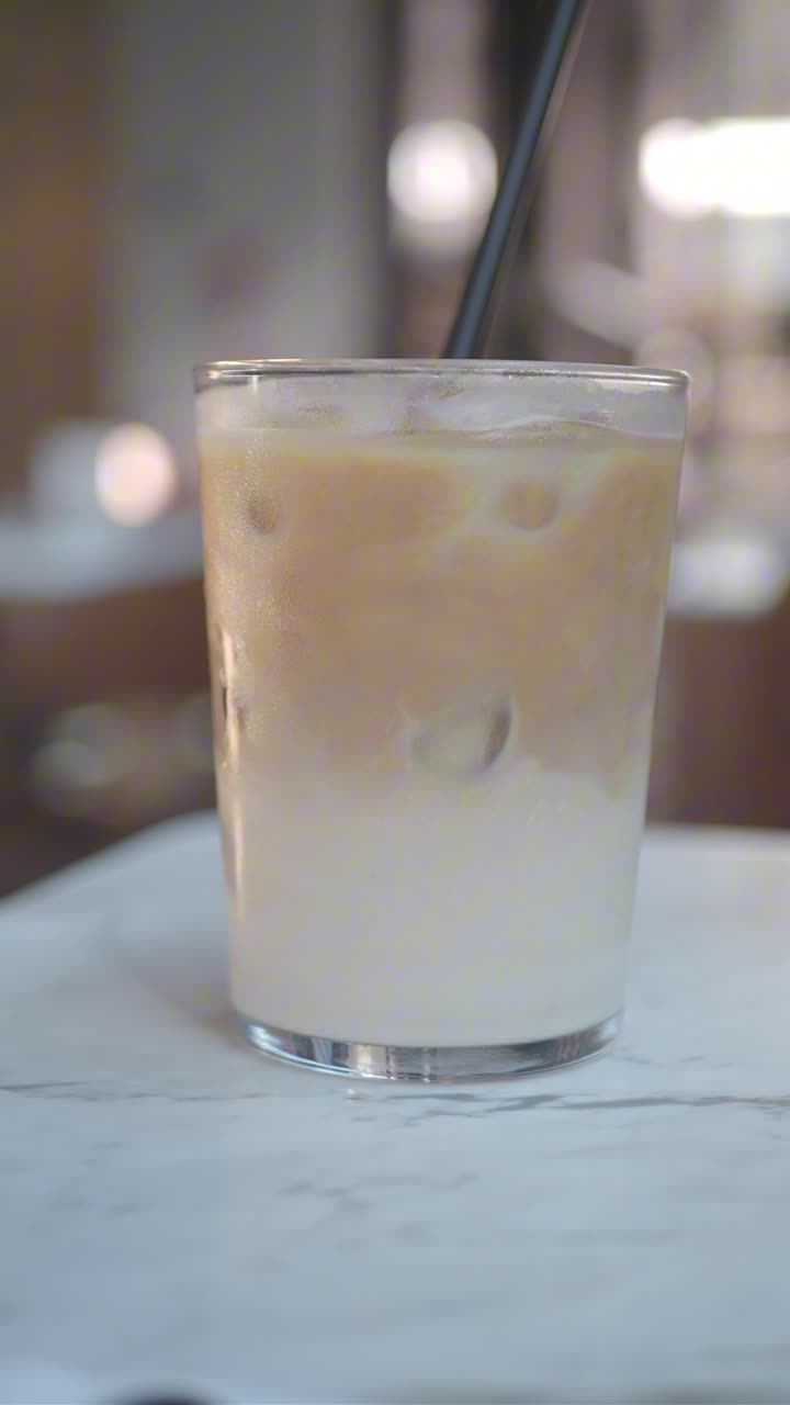 Latte macchiato freddo rinfrescante in un bicchiere su un tavolo di marmo.