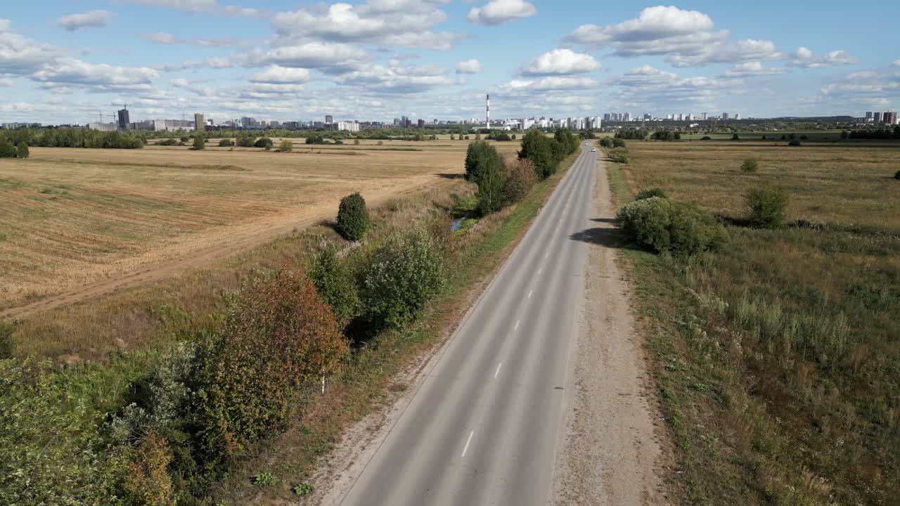 сельская дорога через сельский ландшафт с городом на заднем плане