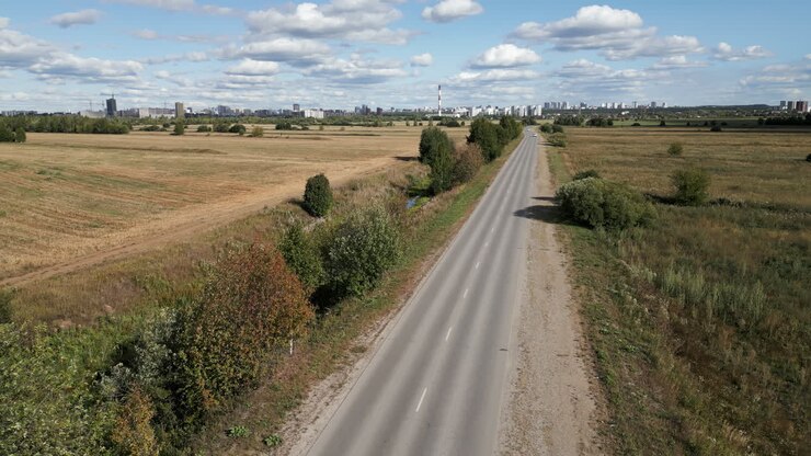 Strada di campagna attraverso un paesaggio rurale con città sullo sfondo