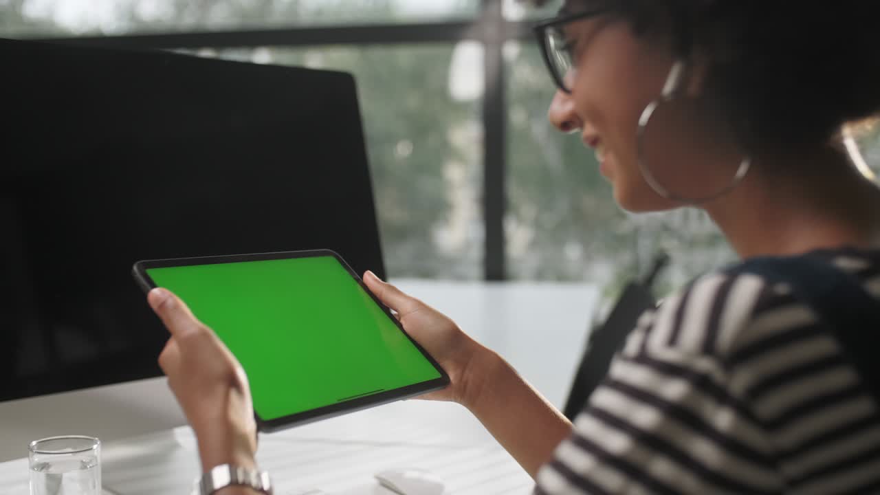 테이블 위에서 사무실 인테리어에서 일하는 비즈니스 여성의 어깨 을 통해, 디스플레이 녹색 화면을보고.
