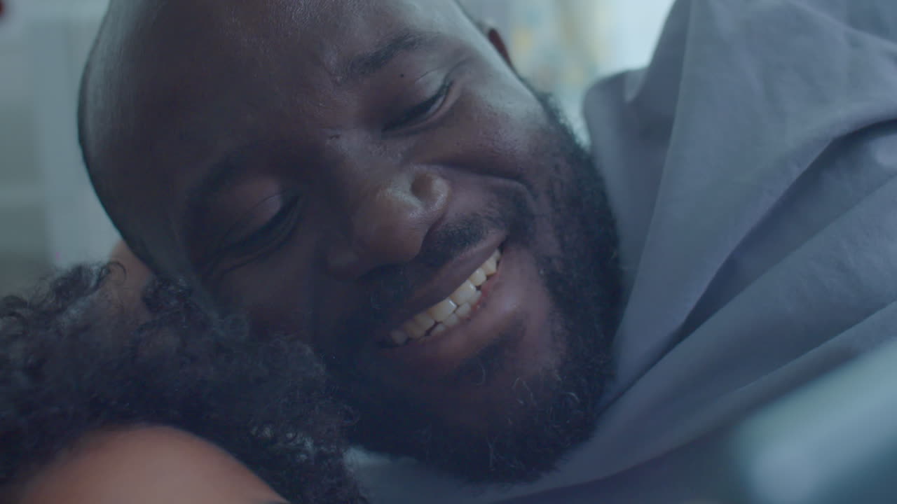 Black Man and Little Son Using Tablet on Bed