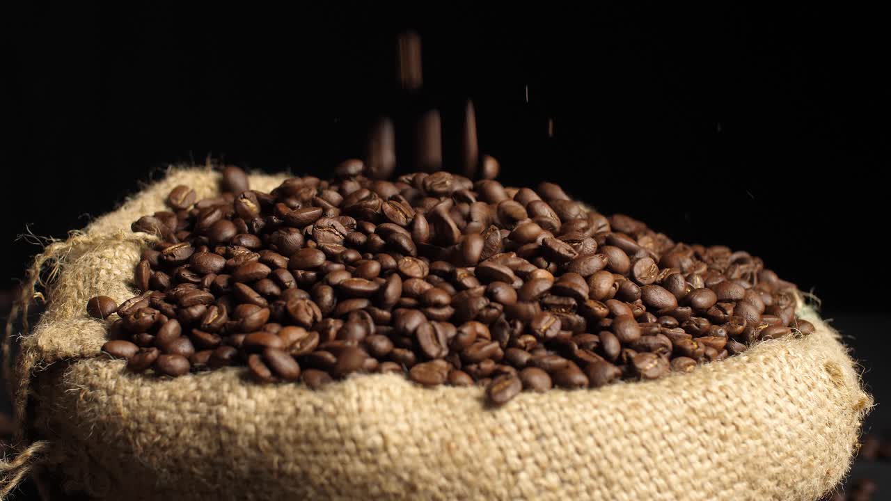 Roasted Coffee Beans Falling On Pile Of Seed In Sack Bag, Video In 4K, 50Fps