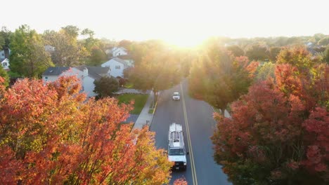 red, orange, yellow locust and maple trees in fall, autumn foliage, cars whiz by in small town america