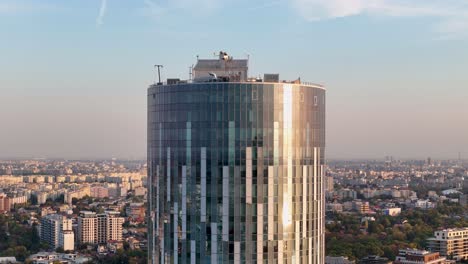 aerial close up of a tall office building with a stunning sunset in the background, bucharest, romania