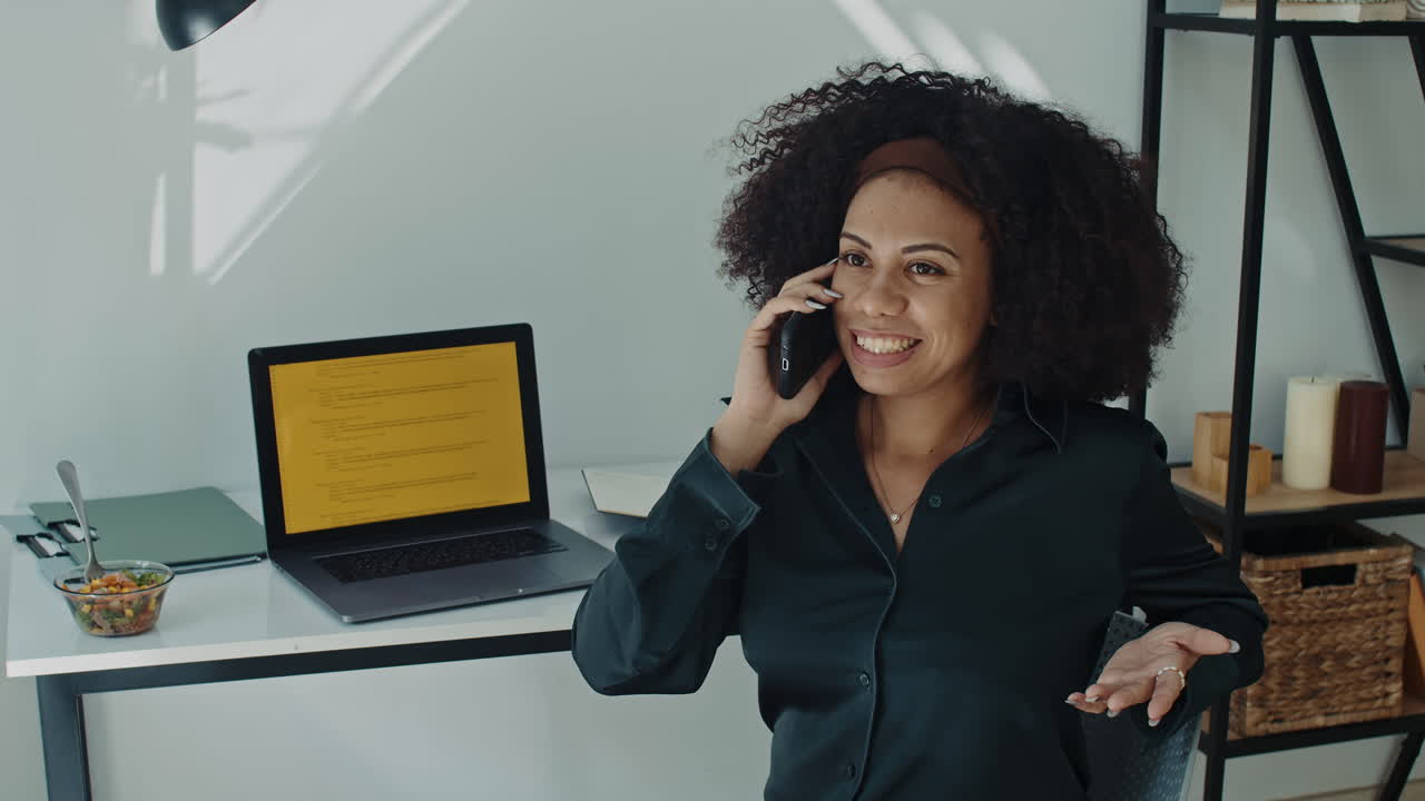 Latin Programmer Chatting on Phone while Coding on Laptop at Home