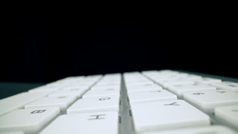 movimiento por encima del teclado de la computadora moderna en el espacio oscuro primer plano