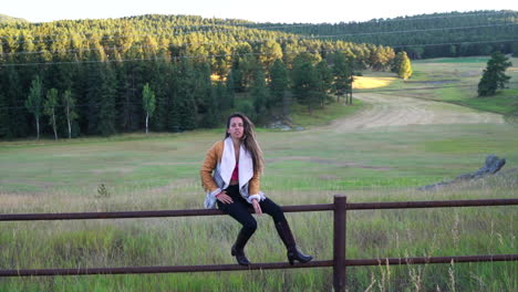cinematic female women model actress cute outfit jacket dark brown hair pose on tall fence yellow grass golden hour denver evergreen colorado open space summer handheld follow