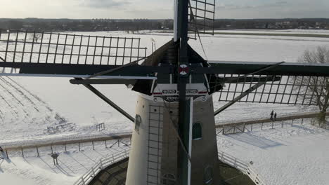 close jib up of traditional dutch windmill, revealing beautiful snow covered meadow