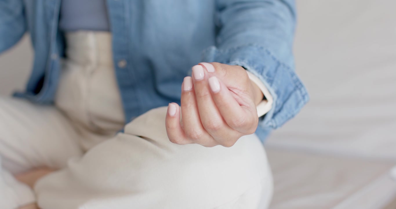 Il movimento del polso di una donna sposta la mano sul divano, le dita si aprono mostrando lo smartwatch per controllare l'ora