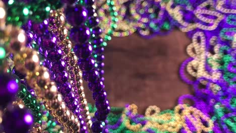 flat lay border of colorful mardi gras beads with more beads hanging on side moving slightly