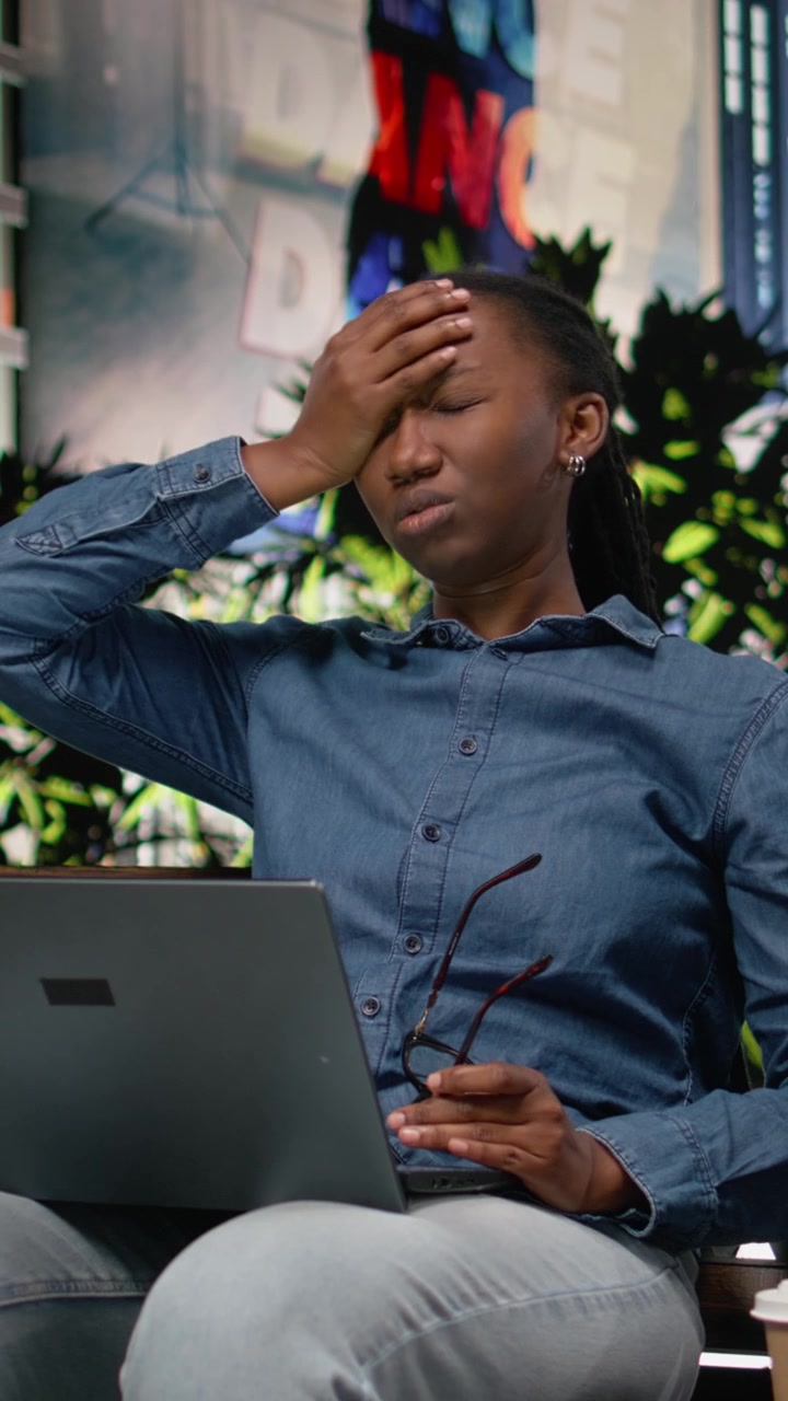 Video verticale: Donna afroamericana preoccupata che fatica a rispettare le scadenze con il laptop.