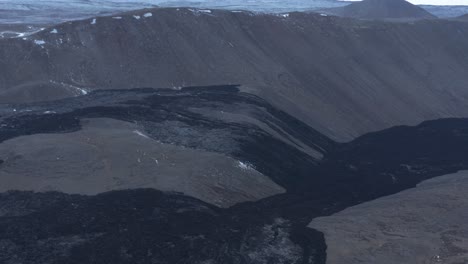 Black-solid-river-of-basalt-rock-through-valley-in-highlands-Iceland,-effusive-volcano