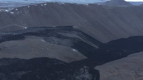 black solid river of basalt rock through valley in highlands iceland, effusive volcano