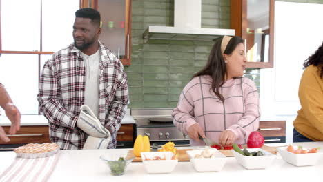 Happy-diverse-male-and-female-friends-preparing-food-together-in-kitchen