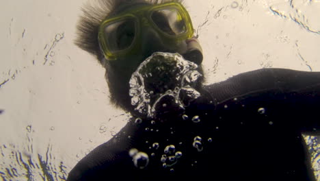 Looking-up-at-a-man-snorkeling-and-blowing-bubbles-under-water