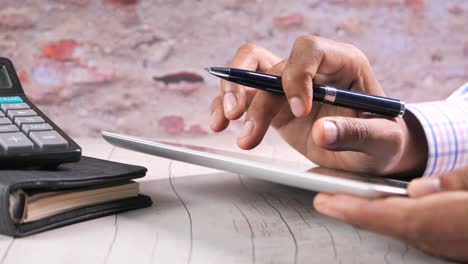 person using a tablet, calculator, and pen