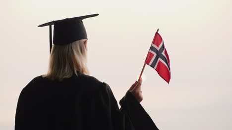 Rückansicht-Eines-Absolventen-Mit-Der-Flagge-Norwegens-In-Der-Hand-Studieren-In-Norwegen