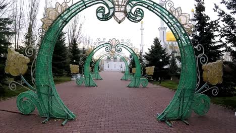 Walking-through-beautiful-arches-in-a-park,-mosque-in-the-background