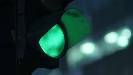 close-up traffic light against the background of the evening city flashes green and changes to orange