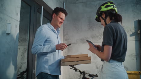 Man receives pizza delivery from courier, completing transaction with smartphones