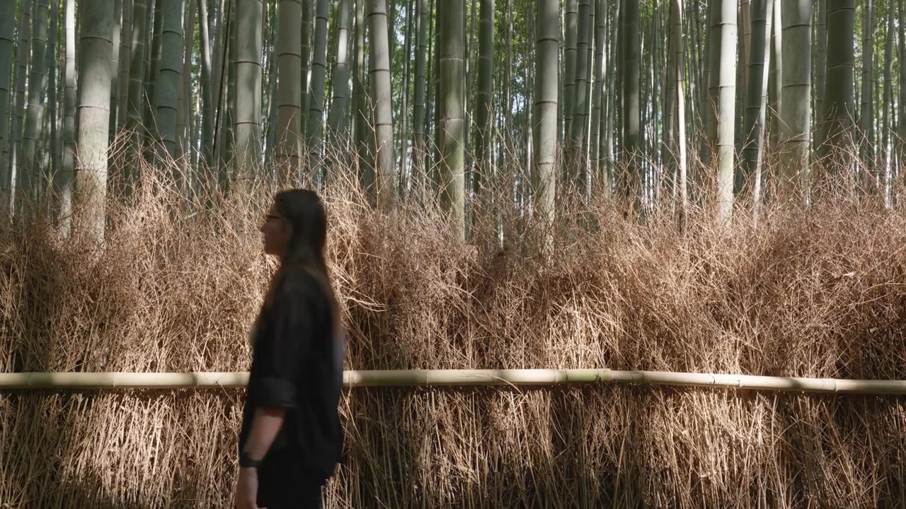 Giovane donna caucasica cammina davanti al bambù ad Arashiyama, Kyoto, Giappone.