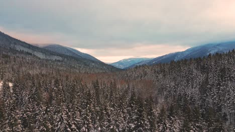 Golden-Hour-in-the-Mystic-Winter:-Beautiful-Drone-Pullback-Shot-of-Snow-Covered-Forests-and-Majestic-Mountains-in-the-Thompson-Nicola-Region,-BC,-Canada