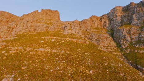 Espectacular-Toma-Aérea-De-Bosques-Vírgenes,-Colinas-Y-Montañas-Contra-Un-Cielo-Azul,-Girando-180-Grados-Para-Mostrar-Ciudad-Del-Cabo-Al-Atardecer