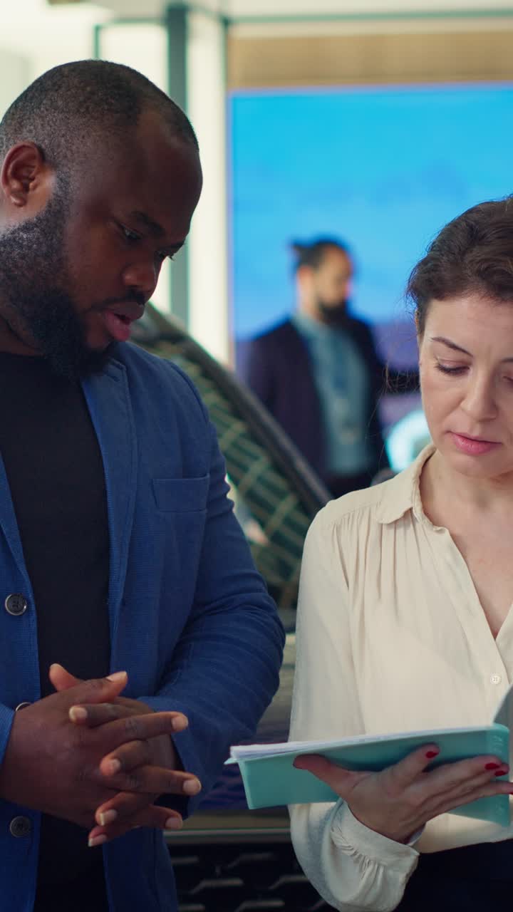 Man and Woman Discussing Documents in Car Dealership