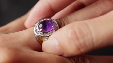 una mano delicada tira suavemente del anillo de ametista púrpura de un dedo