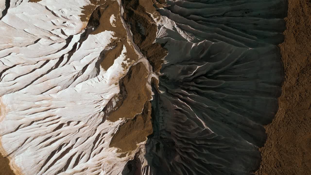 Aerial view of eroded landscape with white and brown geological formations
