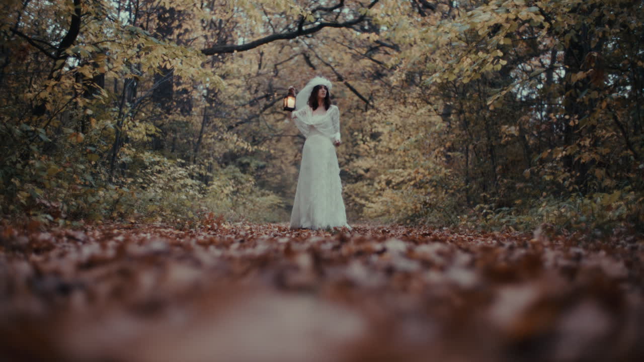 Woman in White Dress Holding Lantern in Autumn Forest