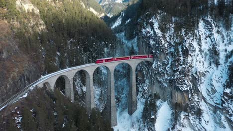 excellent aerial view of a train passing through the landwasser viaduct in switzerland