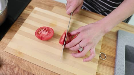 person slicing a tomato on a cutting board