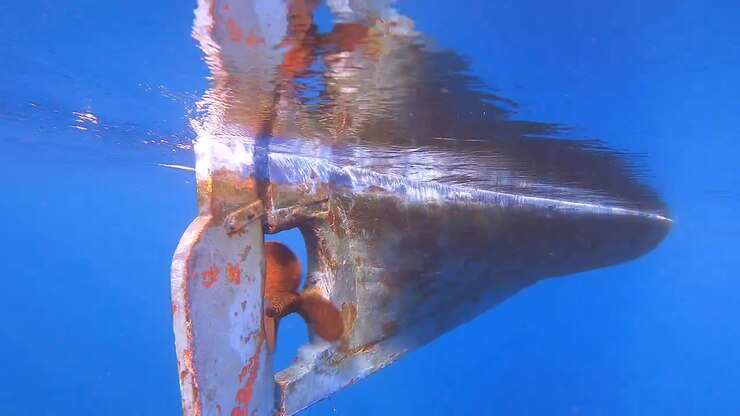 Underwater View of a Boat Propeller and Rudder Moving Through Clear Blue Water