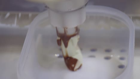 una toma cercana de un brazo mecánico llenando el helado recién hecho en un patrón en un recipiente cuadrado
